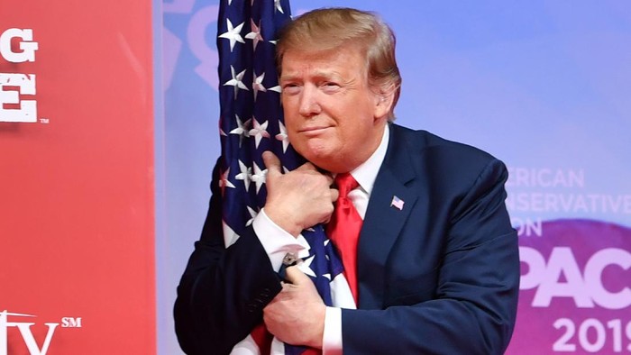 US President Donald Trump hugs the US flag as he arrives to speak at the annual Conservative Political Action Conference (CPAC) in National Harbor, Maryland, on March 2, 2019. (Photo by NICHOLAS KAMM / AFP) / ALTERNATIVE CROP