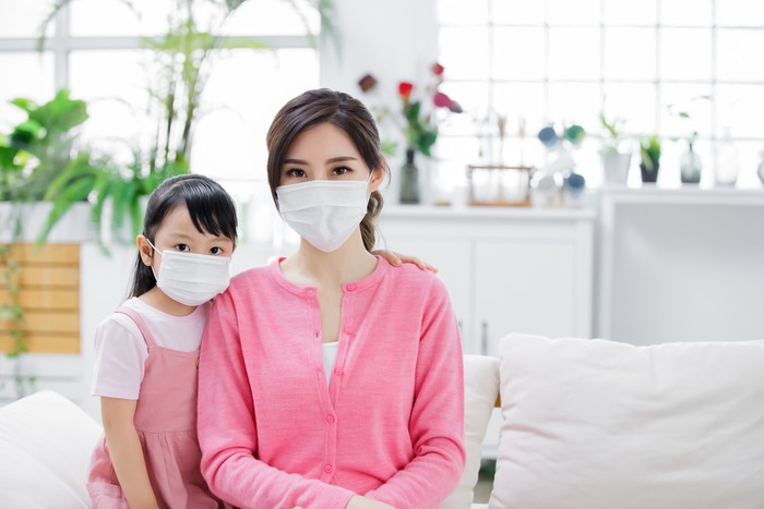 Mom and daughter wear mask to protect themselves from virus infection