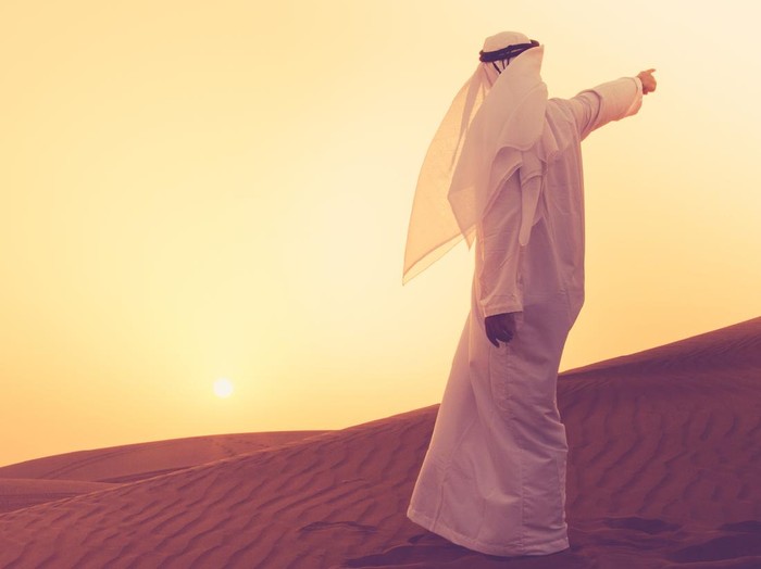 ilustrasi nabi An Arab standing at the sand dunes of Dubai and aiming towards the horizon.