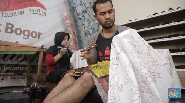 Perajin memproduksi masker batik di Sentra Kerajinan Batik Tradisiku, Kota Bogor, Jawa Barat, Jumat (2/10/2020). Pemerintah tanggal 2 Oktober sebagai Hari Batik Nasional. Penetapan tersebut berlandaskan keputusan Perserikatan Bangsa-Bangsa (PBB) yang menetapkan batik menjadi warisan budaya dunia dari Indonesia. Galeri Batik ini merupakan salah satu pusat di mana pengunjung dapat melihat dan memesan batik yang desainnya amat kental dengan nuansa Kota Bogor. Biasanya wisatawan yang hadir ke Bogor bisa melihat dan mengunjungi Galeri Batik ini. Karena adanya aturan PSBB  membuat turis asing tidak bisa datang. Ragam desainnya pun rupa-rupa mulai dari motif hujan gerimis, kujang, Kebun Raya, Istana Bogor, dan Batu Tulis. Untuk saat ini perajin sedang garap masker dengan motif batik standar SNI. Seperti diketahui Badan Standardisasi Nasional (BSN) mengeluarkan spesifikasi masker kain ber-SNI yang terbagi menjadi tiga tipe berdasarkan penggunaannya, antara lain tipe A untuk penggunaan umum, tipe B untuk penggunaan filtrasi bakteri, dan tipe C untuk penggunaan filtrasi partikel. (CNBC Indonesia/ Muhammad Sabki