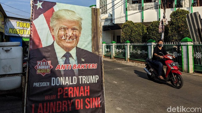 Meme Presiden Trump Belum Pernah Mencuci Baju di Ciputat Warga melintas di depan baliho laundry bergambar meme Presiden AS, Donald Trump di Ciputat Timur, Tangerang Selatan, Jumat (2/10/2020). Trik marketing tersebut bertuliskan Presiden Trump belum pernah mencuci baju di tempat tersebut. Saat ini Trump sedang mempertahankam kursinya dari penantang Joe Biden. (Ari Saputra detikcom).