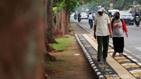 Dua orang warga melintas di jalur pedestrian yang dihiasi aneka gambar unik.
