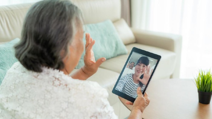 Asian elderly woman virtual happy hour meeting and talking online together with her daughter in video conference with tablet for a online meeting in video call for social distancing.