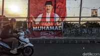 Pengendara sepeda motor melintas di depan spanduk salah satu calon Wali Kota Tangsel.