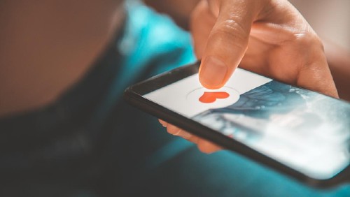 Finger of woman pushing heart icon on screen in mobile smartphone application. Online dating app, valentines day concept.