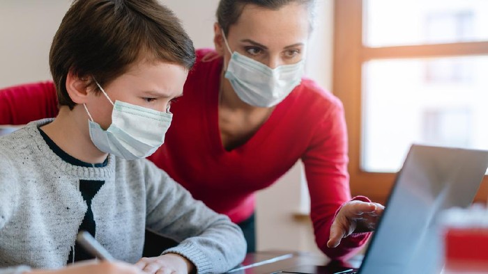 1213773243 Mother and son in video chat with school teacher wearing masks