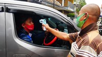 Seorang warga memeriksa suhu tubuh warga di tengah penerapan mini lockdown di Kota Cimahi, Jawa Barat, Senin (5/10/2020).