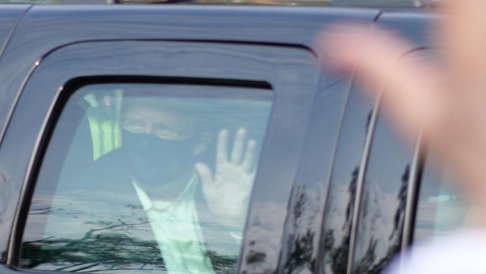 President Donald Trump drives past supporters gathered outside Walter Reed National Military Medical Center in Bethesda, Md., Sunday, Oct. 4, 2020. Trump was admitted to the hospital after contracting COVID-19. (AP Photo/Anthony Peltier)