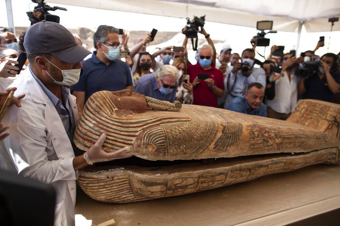 Penampakan Isi Satu dari 59 Sarkofagus yang Ditemukan Mesir Khalid el-Anany, Egyptβs tourism and antiquities minister, right, and Mostafa Waziri, secretary-general of the countryβs Supreme Council of Antiquities, left, stand over a sarcophagus at the Saqqara archaeological site, 30 kilometers (19 miles) south of Cairo, Egypt on Saturday, Oct. 3, 2020. El-Anany says at least 59 sealed sarcophagi with mummies inside were found in three wells at the vast necropolis, believed to have been buried there more than 2,600 years ago. (AP Photo/Mahmoud Khaled)