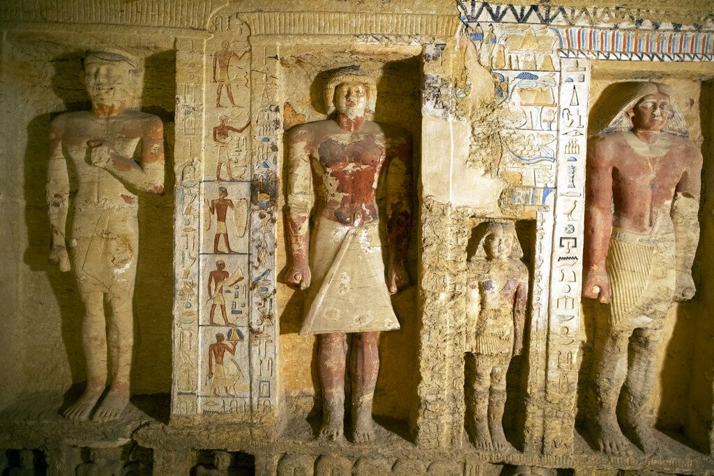 Khalid el-Anany, Egypt's tourism and antiquities minister, right, and Mostafa Waziri, secretary-general of the country's Supreme Council of Antiquities, left, stand over a sarcophagus at the Saqqara archaeological site, 30 kilometers (19 miles) south of Cairo, Egypt on Saturday, Oct. 3, 2020. El-Anany says at least 59 sealed sarcophagi with mummies inside were found in three wells at the vast necropolis, believed to have been buried there more than 2,600 years ago. (AP Photo/Mahmoud Khaled)