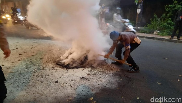 Polisi memadamkan ban yang dibakar massa aksi di Gejayan, Sleman, Senin (5/10/2020).