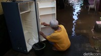 Seorang warga membersihkan lemari es nya yang sempat terendam banjir.
