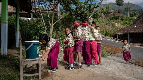 YOGYAKARTA, INDONESIA - SEPTEMBER 28: Kharisma Anisa Putri (14), uses her broke screen smartphone for studying online using free wifi provided by the village as to help parents with financial difficulties, they pay 30,000 Indonesian Rupiah or around (USD 2) per month amid the Coronavirus pandemic on September 28, 2020 in Yogyakarta, Indonesia. According to the Indonesian Ministry of Education and Culture data nearly 70 million children have been affected by school shutdowns which started in mid-March. Since it closed on March 16, the school has implemented various methods and approaches to support distance learning. Even so, its implementation in the field still faces various obstacles. The problem is limited support facilities, such as laptops, smart phones, and internet data packages. In addition, parents also claim to not have enough time and feel they lack the knowledge to accompany children to learn online. Indonesia is struggling to contain thousands of new daily cases of coronavirus amid easing of rules to allow economic activity to resume. (Photo by Ulet Ifansasti/Getty Images)