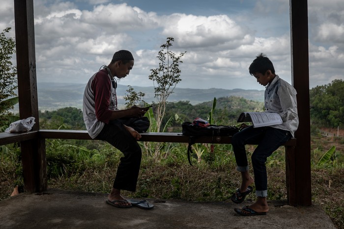 Potret Sistem Pendidikan Indonesia di Tengah Pandemi YOGYAKARTA, INDONESIA - SEPTEMBER 28: Kharisma Anisa Putri (14), uses her broke screen smartphone for studying online using free wifi provided by the village as to help parents with financial difficulties, they pay 30,000 Indonesian Rupiah or around (USD 2) per month amid the Coronavirus pandemic on September 28, 2020 in Yogyakarta, Indonesia. According to the Indonesian Ministry of Education and Culture data nearly 70 million children have been affected by school shutdowns which started in mid-March. Since it closed on March 16, the school has implemented various methods and approaches to support distance learning. Even so, its implementation in the field still faces various obstacles. The problem is limited support facilities, such as laptops, smart phones, and internet data packages. In addition, parents also claim to not have enough time and feel they lack the knowledge to accompany children to learn online. Indonesia is struggling to contain thousands of new daily cases of coronavirus amid easing of rules to allow economic activity to resume. (Photo by Ulet Ifansasti/Getty Images)