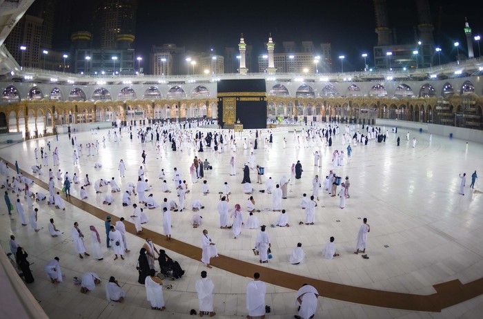 CLARIFIES THAT THE UMRAH PILGRIMAGE CAN BE UNDERTAKEN AT ANY TIME OF THE YEAR -- In this photo released by Saudi Ministry of Hajj and Umrah, Muslims practice social distancing while praying around the Kaaba, the cubic building at the Grand Mosque during the first day umrah pilgrimages were allowed to restart, in the Muslim holy city of Mecca, Saudi Arabia, Sunday, Oct. 4, 2020. The umrah pilgrimage, or smaller pilgrimage, can be undertaken at any time of the year. A very small, limited number of people donning the white terrycloth garment symbolic of the Muslim pilgrimage circled Islams holiest site in Mecca on Sunday after Saudi Arabia lifted coronavirus restrictions that had been in place for months. (Saudi Ministry of Hajj and Umrah via AP)