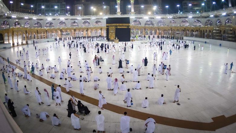 Umroh Kembali Dibuka, Begini Suasananya CLARIFIES THAT THE UMRAH PILGRIMAGE CAN BE UNDERTAKEN AT ANY TIME OF THE YEAR -- In this photo released by Saudi Ministry of Hajj and Umrah, Muslims practice social distancing while praying around the Kaaba, the cubic building at the Grand Mosque during the first day umrah pilgrimages were allowed to restart, in the Muslim holy city of Mecca, Saudi Arabia, Sunday, Oct. 4, 2020. The umrah pilgrimage, or smaller pilgrimage, can be undertaken at any time of the year. A very small, limited number of people donning the white terrycloth garment symbolic of the Muslim pilgrimage circled Islams holiest site in Mecca on Sunday after Saudi Arabia lifted coronavirus restrictions that had been in place for months. (Saudi Ministry of Hajj and Umrah via AP)