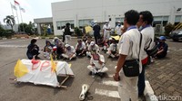 Para buruh menggelar aksi dengan tetap mengenakan seragam pabrik.