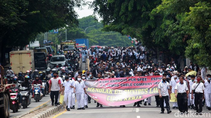 Para pekerja pabrik  melakukan aksi unjuk rasa dengan berjalan kaki di Jl Gatot Subroto, Jatiuwung, Kota Tangerang, Banten, Selasa (06/10/2020). Akibatnya, arus lalu-lintas sempat tersendat Karena jalan dikuasai massa. Unjuk rasa terkait pengesahan UU Cipta Karya oleh DPR RI