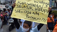 Para buruh membawa atribut aksi seperti poster dan spanduk.