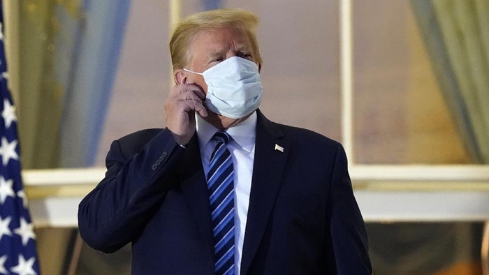 President Donald Trump removes his mask as he stands on the balcony outside of the Blue Room as returns to the White House Monday, Oct. 5, 2020, in Washington, after leaving Walter Reed National Military Medical Center, in Bethesda, Md. Trump announced he tested positive for COVID-19 on Oct. 2. (AP Photo/Alex Brandon)
