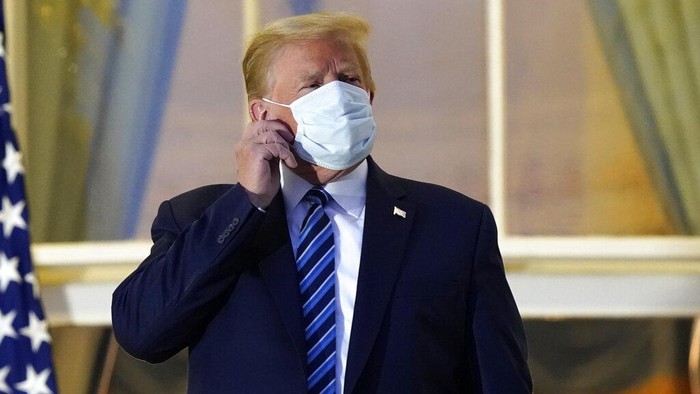 President Donald Trump removes his mask as he stands on the balcony outside of the Blue Room as returns to the White House Monday, Oct. 5, 2020, in Washington, after leaving Walter Reed National Military Medical Center, in Bethesda, Md. Trump announced he tested positive for COVID-19 on Oct. 2. (AP Photo/Alex Brandon)