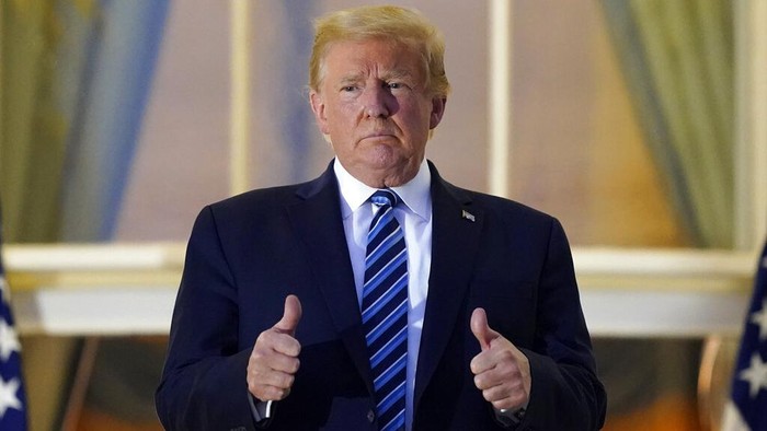 President Donald Trump removes his mask as he stands on the balcony outside of the Blue Room as returns to the White House Monday, Oct. 5, 2020, in Washington, after leaving Walter Reed National Military Medical Center, in Bethesda, Md. Trump announced he tested positive for COVID-19 on Oct. 2. (AP Photo/Alex Brandon)