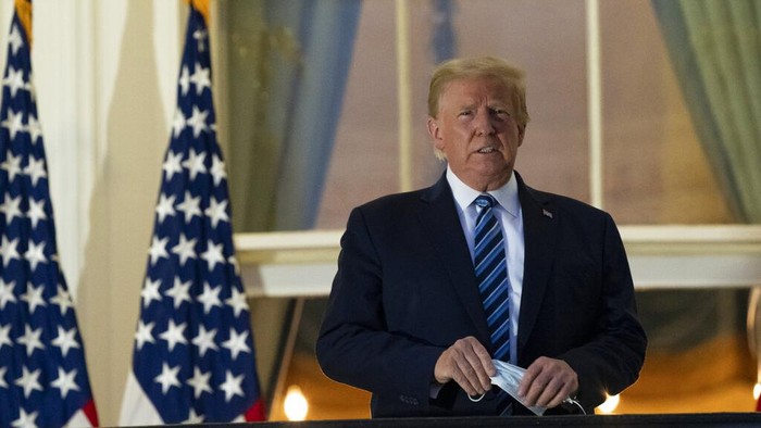 President Donald Trump removes his mask as he stands on the balcony outside of the Blue Room as returns to the White House Monday, Oct. 5, 2020, in Washington, after leaving Walter Reed National Military Medical Center, in Bethesda, Md. Trump announced he tested positive for COVID-19 on Oct. 2. (AP Photo/Alex Brandon)