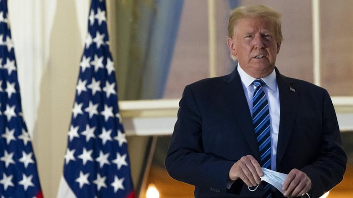 President Donald Trump removes his mask as he stands on the balcony outside of the Blue Room as returns to the White House Monday, Oct. 5, 2020, in Washington, after leaving Walter Reed National Military Medical Center, in Bethesda, Md. Trump announced he tested positive for COVID-19 on Oct. 2. (AP Photo/Alex Brandon)
