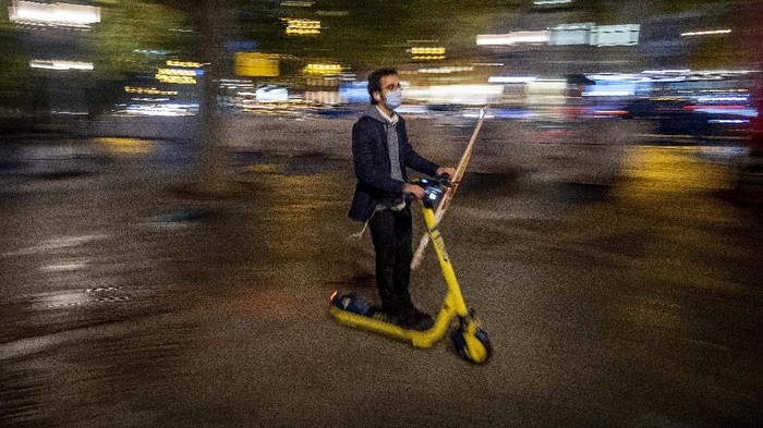 A man wearing a face mask to protect against coronavirus, as he drives his E-scooter in central Frankfurt, Germany, Monday, Oct. 5, 2020. (AP Photo/Michael Probst)