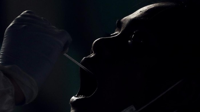 A resident undergoes a free COVID-19 swab test in a low income area in Manila, Philippines, Tuesday, Oct. 6, 2020. The city government is providing free swab tests to tricycle and passenger Jeepney drivers in the area in hopes of curbing the spread of the coronavirus. (AP Photo/Aaron Favila)