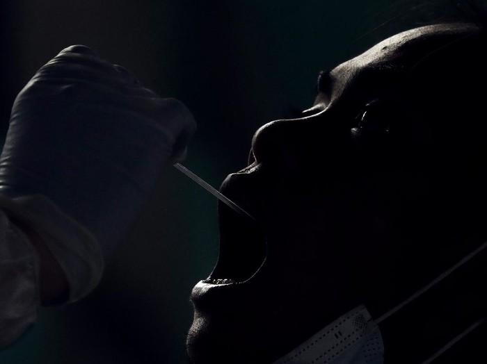A resident undergoes a free COVID-19 swab test in a low income area in Manila, Philippines, Tuesday, Oct. 6, 2020. The city government is providing free swab tests to tricycle and passenger Jeepney drivers in the area in hopes of curbing the spread of the coronavirus. (AP Photo/Aaron Favila)
