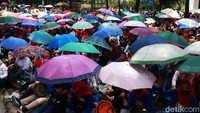 Massa buruh kompak membawa payung warna-warna dalam aksi yang berlangsung di depan Balai Kota Bandung.