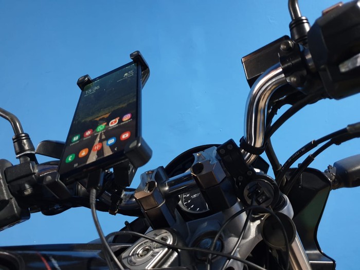 Ilustrasi ngecas handphone di motor
