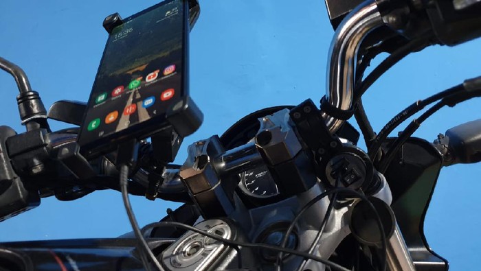 Ilustrasi ngecas handphone di motor