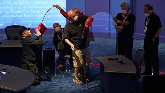 Workers clean protective plastic panels onstage between tables for Vice President Mike Pence and Democratic vice presidential candidate, Sen. Kamala Harris, D-Calif., as preparations take place for the vice presidential debate in Kingsbury Hall at the University of Utah, Tuesday, Oct. 6, 2020, in Salt Lake City. (AP Photo/Patrick Semansky)