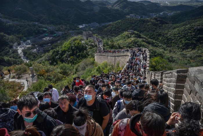 BEIJING, CHINA - OCTOBER 04: A Chinese tourist poses as her photo is taken by a friend as they visit a crowded section of the Great Wall at Badaling after tickets sold out during the Golden Week holiday on October 4, 2020 in Beijing, China. Officials are expecting the Golden Week holiday to boost Chinas consumer economy as people were encouraged to use the eight-day break to travel and spend. Tourist sites including the Great Wall were packed, with tickets selling out most days given pandemic restrictions and capacity capped at 75%. (Photo by Kevin Frayer/Getty Images)