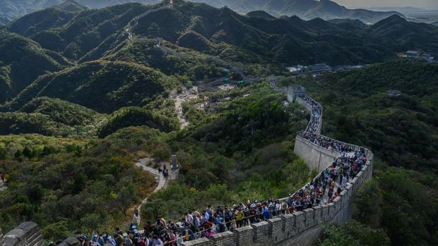 BEIJING, CHINA - OCTOBER 04: A Chinese tourist poses as her photo is taken by a friend as they visit a crowded section of the Great Wall at Badaling after tickets sold out during the 'Golden Week' holiday on October 4, 2020 in Beijing, China. Officials are expecting the Golden Week holiday to boost China's consumer economy as people were encouraged to use the eight-day break to travel and spend. Tourist sites including the Great Wall were packed, with tickets selling out most days given pandemic restrictions and capacity capped at 75%. (Photo by Kevin Frayer/Getty Images)