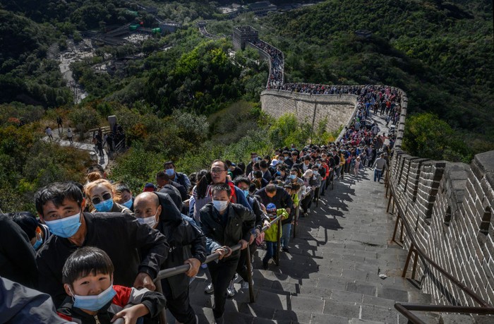 Tembok Besar China Penuh Wisatawan Saat Libur Nasional BEIJING, CHINA - OCTOBER 04: A Chinese tourist poses as her photo is taken by a friend as they visit a crowded section of the Great Wall at Badaling after tickets sold out during the 'Golden Week' holiday on October 4, 2020 in Beijing, China. Officials are expecting the Golden Week holiday to boost China's consumer economy as people were encouraged to use the eight-day break to travel and spend. Tourist sites including the Great Wall were packed, with tickets selling out most days given pandemic restrictions and capacity capped at 75%. (Photo by Kevin Frayer/Getty Images)