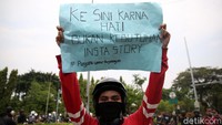 Seorang demonstran membentangkan poster di sela-sela aksi menolak (UU) Omnibus Law Cipta Kerja (Ciptaker).