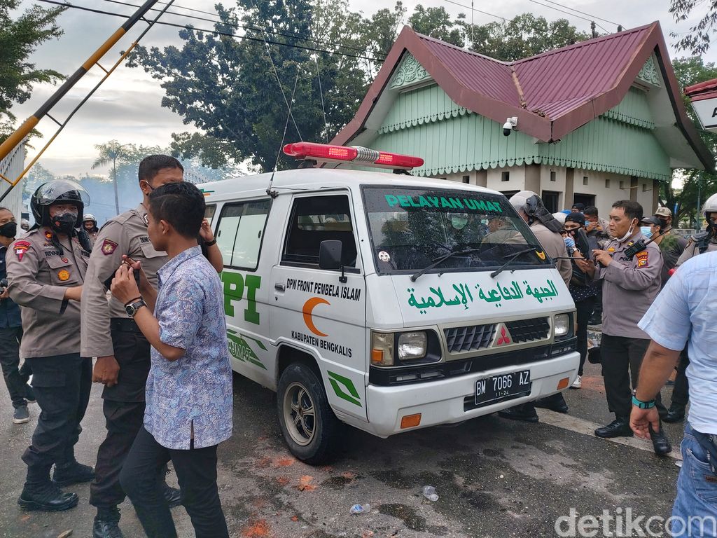 Ambulans bertuliskan FPI ditahan aparat karena menerobos kerumunan massa yang demo tolak Omnibus Law di DPRD Riau. Dua orang diamankan (Chaidir Tanjung/detikcom)