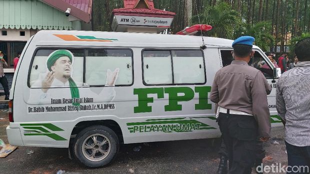 Ambulans bertuliskan FPI ditahan aparat karena menerobos kerumunan massa yang demo tolak Omnibus Law di DPRD Riau. Dua orang diamankan (Chaidir Tanjung/detikcom)