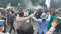 Sementara itu, petugas kepolisian nampak membuat barikade dengan berdiri bergandengan tangan di depan barisan mahasiswa. Di belakang barisan polisi, petugas TNI juga membuat barikade.