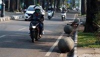 Sejumlah batu granit berbentuk bulat berantakan di bahu jalan.