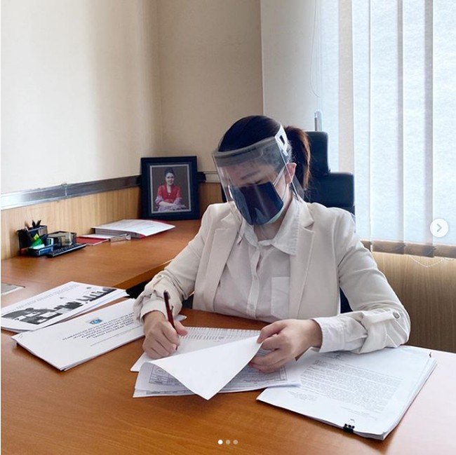 Berada di ruangan kerjanya untuk membuat laporan hasil pengumpulan data mengenai banjir, Tina Toon mengunggah foto yang memperlihatkan penampilannya memakai busana serba putih. Dia bekerja di kantor dengan tetap memakai face shield dan masker. Foto: Instagram @tinatoon101