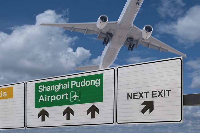 Road sign indicating the direction of Shanghai Pudong airport and a plane that just got up.