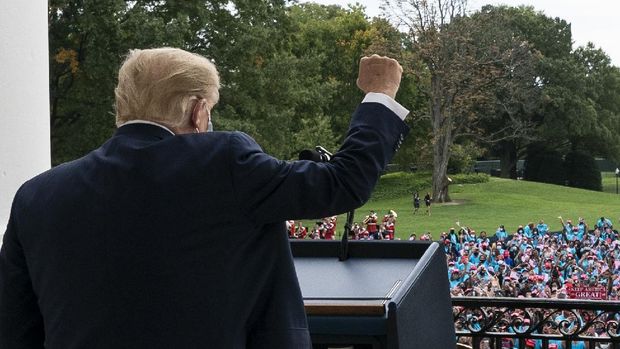 Dengan dua perban di tangan, Presiden Donald Trump menunjuk dari balkon Ruang Biru Gedung Putih saat dia berbicara kepada kerumunan pendukung di Washington, DC, pada hari Sabtu, Oktober 2020.  (Foto AP / Alex Brandon)