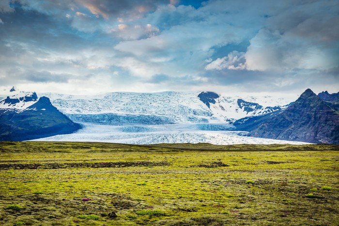 Skeidarajökull Galcier under beautiful summer skyscape. Skeiðarárjökull Glacier is a large outlet glacier draining south from Iceland’s largest ice cap Vatnajökull. Green volcanic plain in the foreground.Skeidarajökull Glacier, Hornafjörður, Vatnajökull National Park, Route 1, Southern Iceland, Iceland, Nordic Countries, Europe