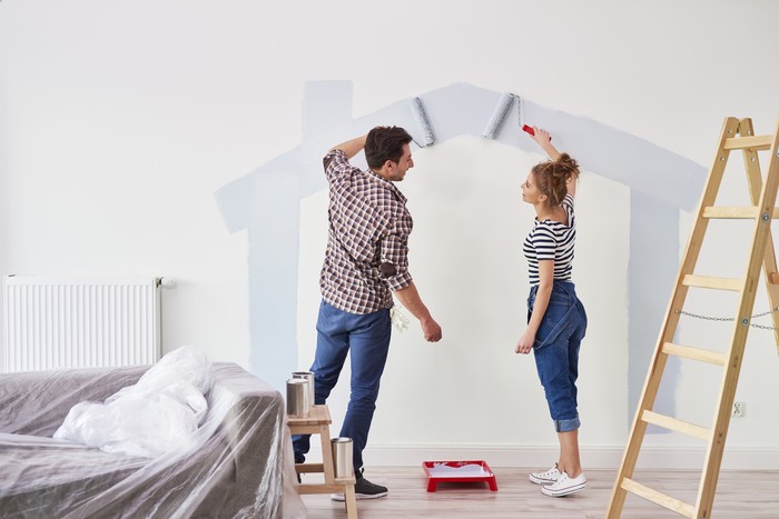Young couple painting the interior wall in their new apartment