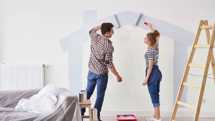 Young couple painting the interior wall in their new apartment