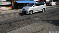 Para pengendara melambatkan laju kendaraannya saat melintas di jalan yang rusak.